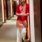 Man wearing a red kurta with white pants in a hallway